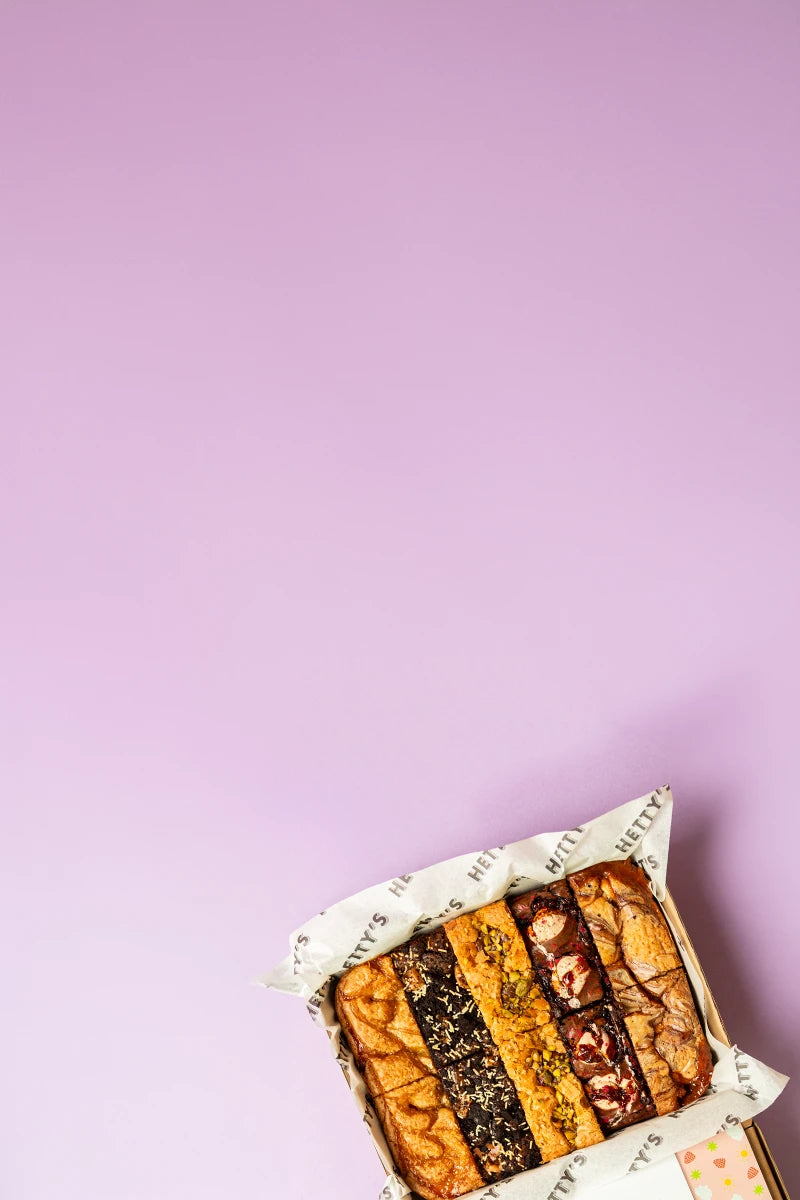 A purple background with a box of assorted brownies