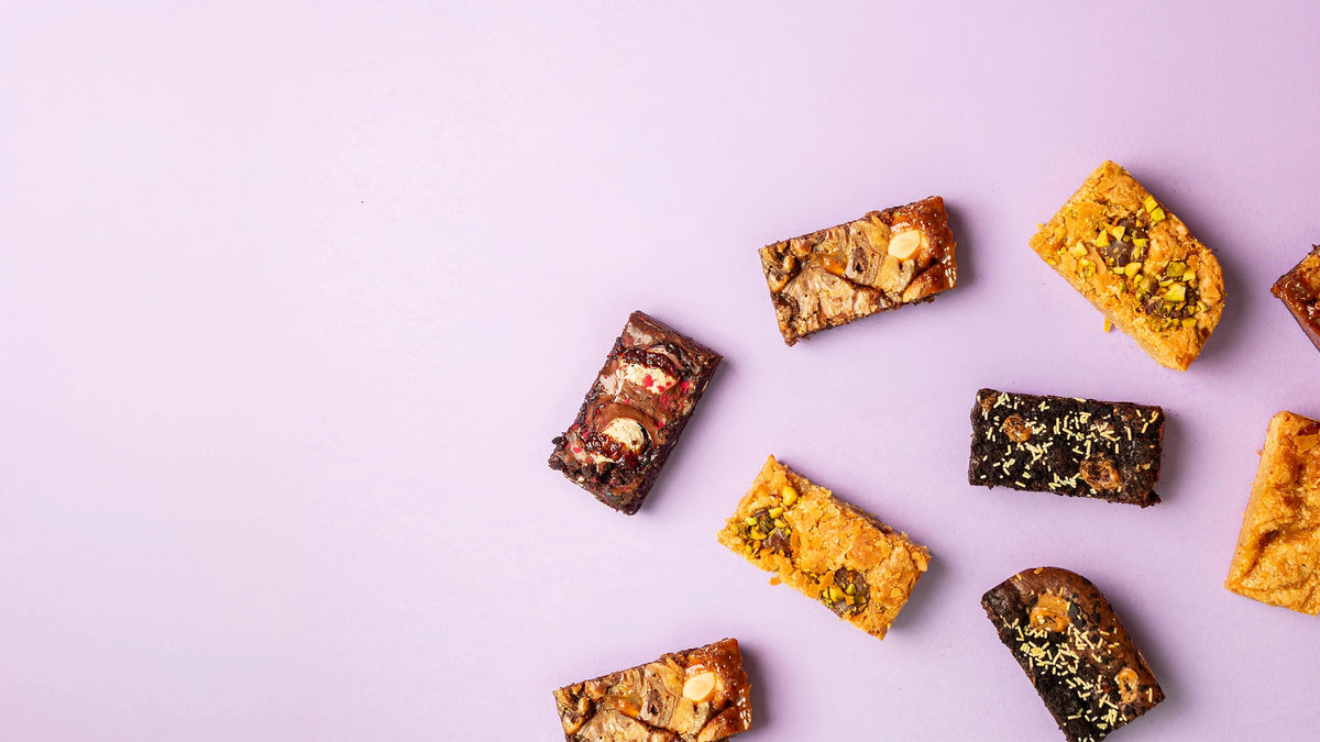 Assorted brownie slices are arranged on light purple background