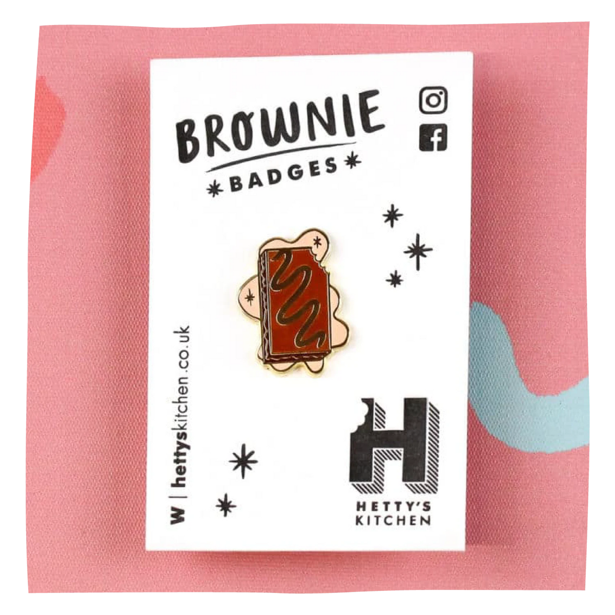 A brownie pin badge by Hetty's Kitchen, featuring a rectangular brownie with wavy chocolate drizzle, mounted on a white display card