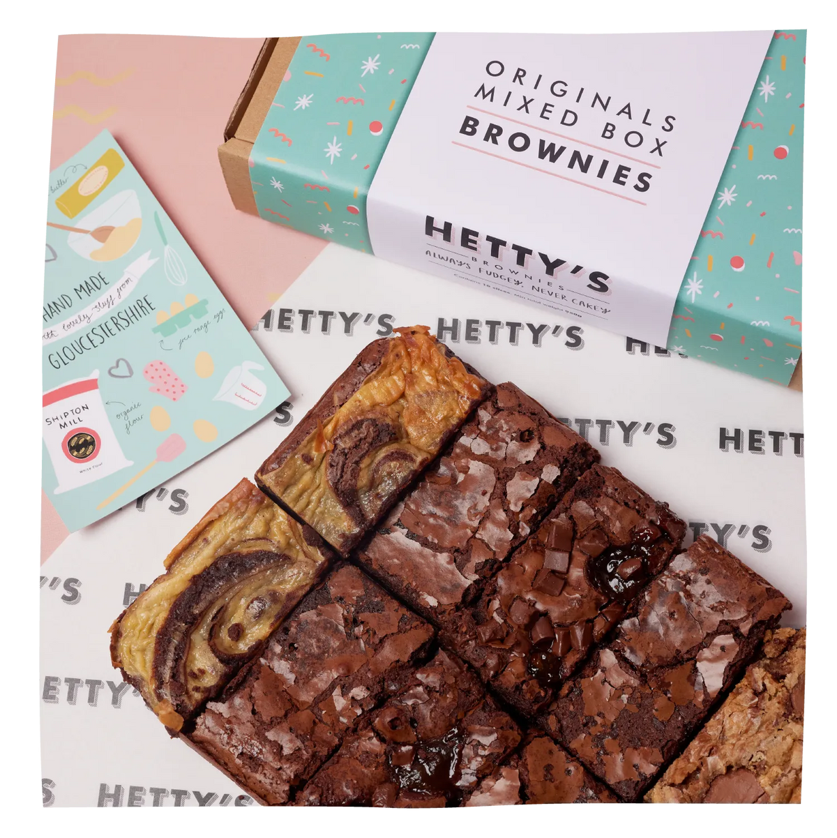 A boxed mix of brownies and a small card on a pastel pink background. The box is mint green with confetti and reads 'ORIGINALS MIXED BOX BROWNIES' and 'HETTY'S'.