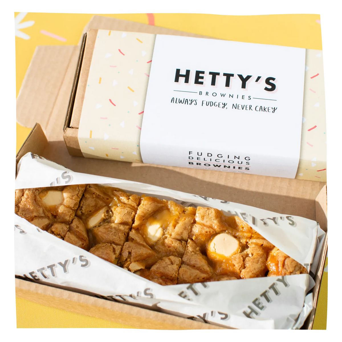 An open box of Hetty's Brownies with a branded paper band, showing cut brownie bars inside.