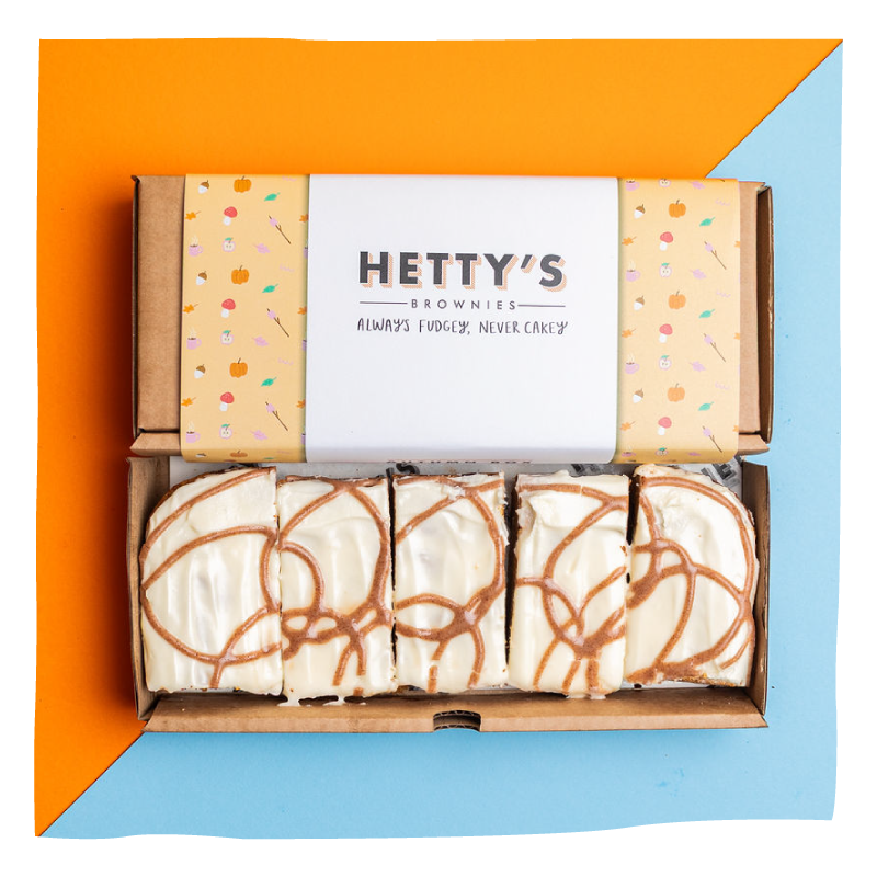 An open cardboard box of brownies with a branded paper label reading 'HETTY'S BROWNIES' on top. 