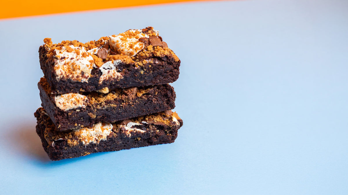 Three stacked square brownies on a light blue background with a small orange area at the top.